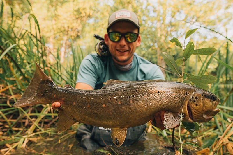 Luka holding a large fish in green riverside cover