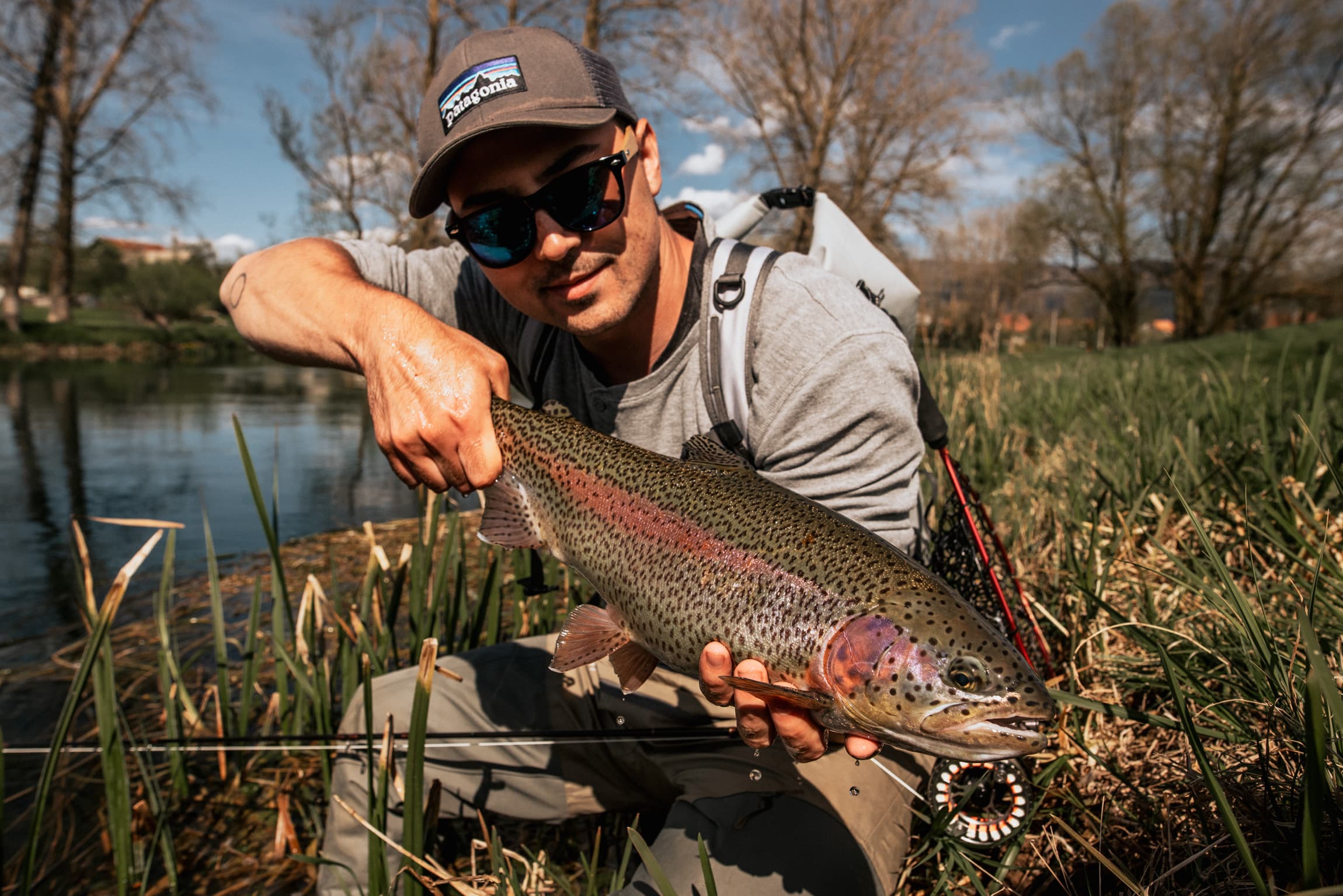 Goran holding a rainbow trout at the riverbank